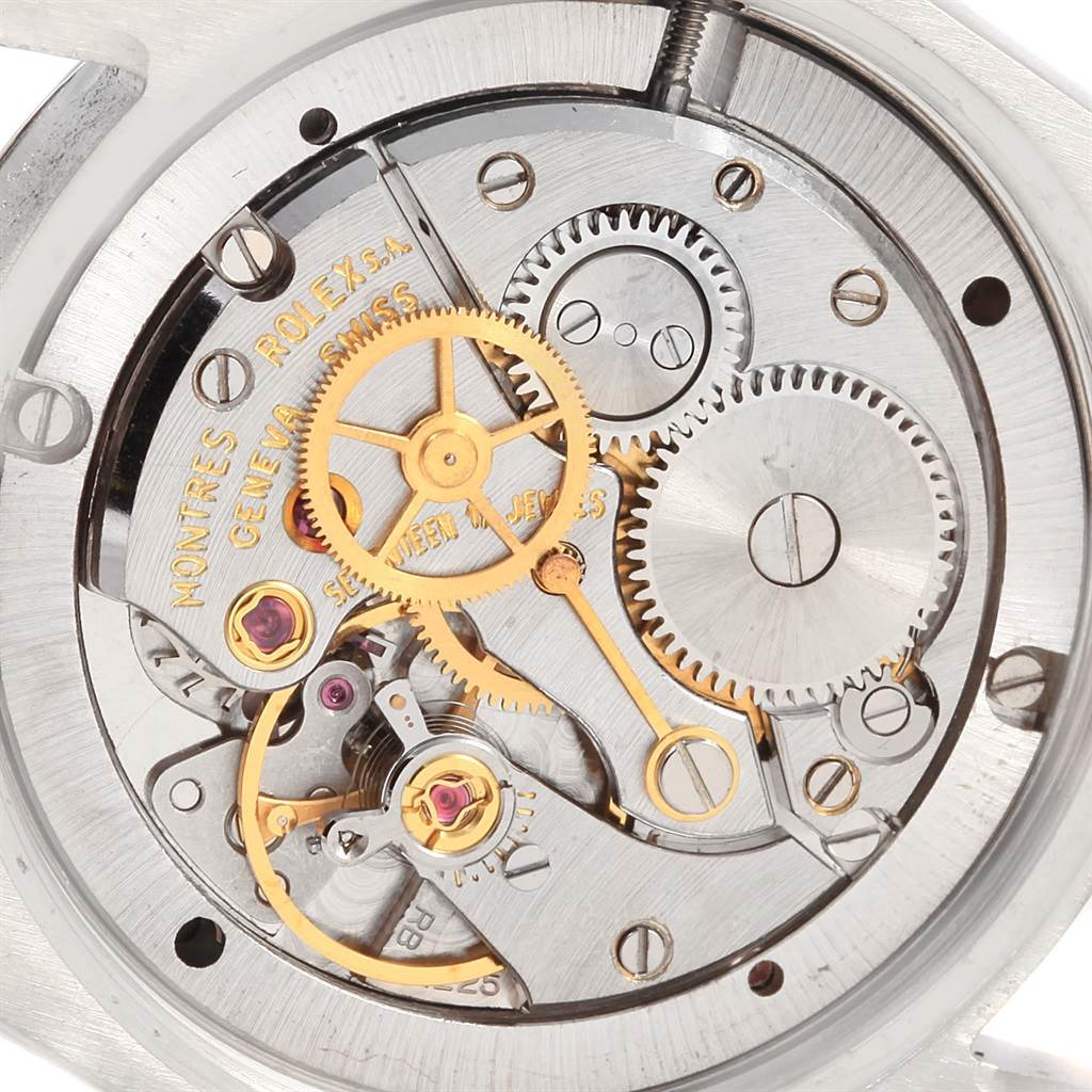 The image shows the internal mechanical movement from the back of a Vintage Collection Rolex watch with intricate gears visible.