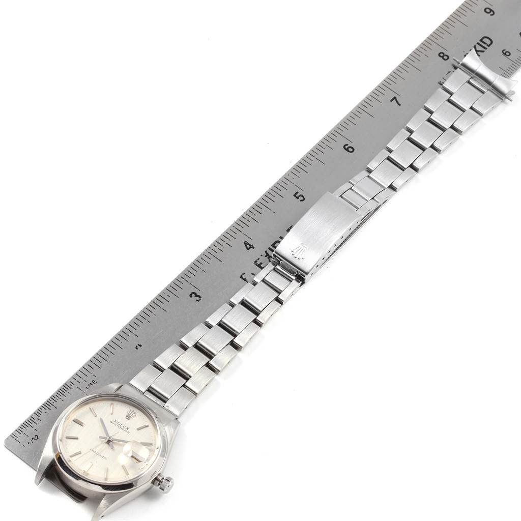 The image shows a Rolex Vintage Collection 6694 Men
s Stainless Steel Silver Dial 6694 Men
s Stainless Steel Silver Dial watch and its stainless steel bracelet laid flat next to a measuring ruler.