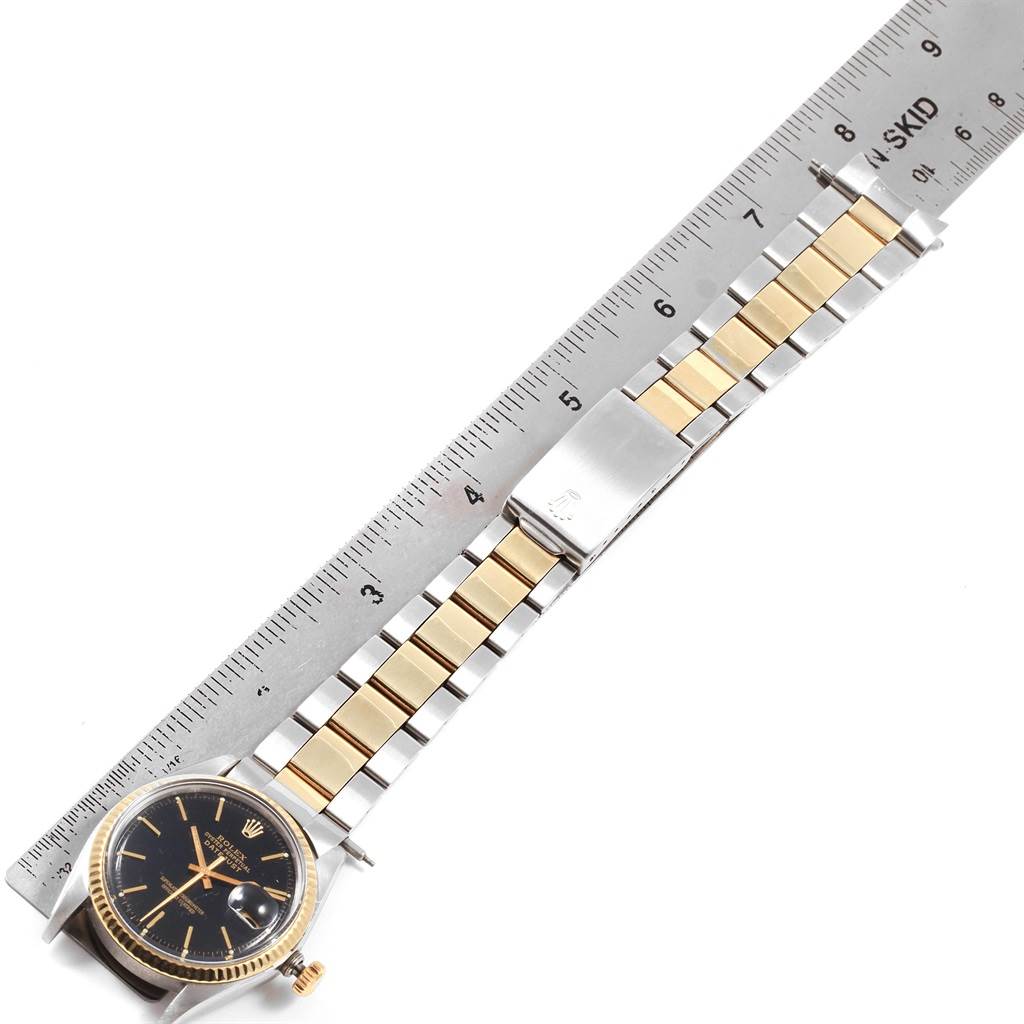 The image shows a Rolex Vintage Collection 1601 Men's Steel and Gold (two tone) Black Dial 1601 Men's Steel and Gold (two tone) Black Dial watch laid flat with a metallic ruler alongside it, displaying the entire bracelet and watch face.