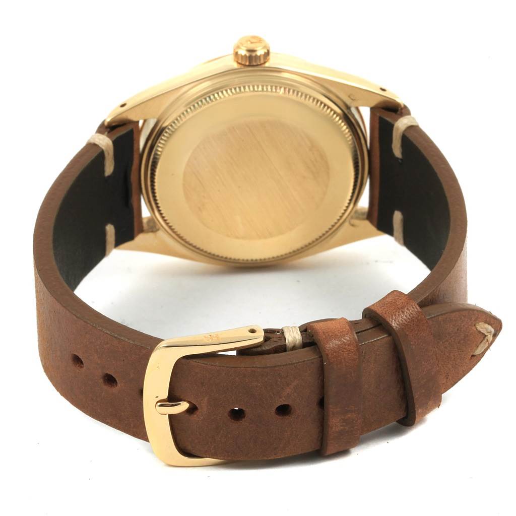 This image shows the back and strap of a Rolex Vintage Collection 1500 Men
s Yellow Gold Silver Dial 1500 Men
s Yellow Gold Silver Dial model watch, highlighting its gold casing and brown leather strap.