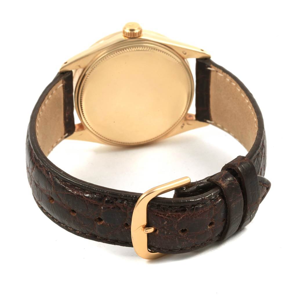 The image shows the back view of a Vintage Collection Rolex watch, highlighting its case, crown, and leather strap with a gold buckle.