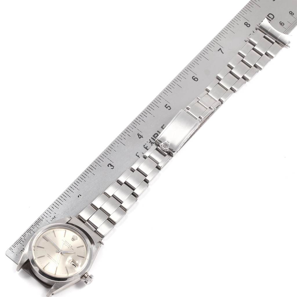 The image shows a Rolex Vintage Collection 1500 Stainless Steel Silver Dial 1500 Stainless Steel Silver Dial watch and its metal bracelet next to a measuring ruler, viewed from above.