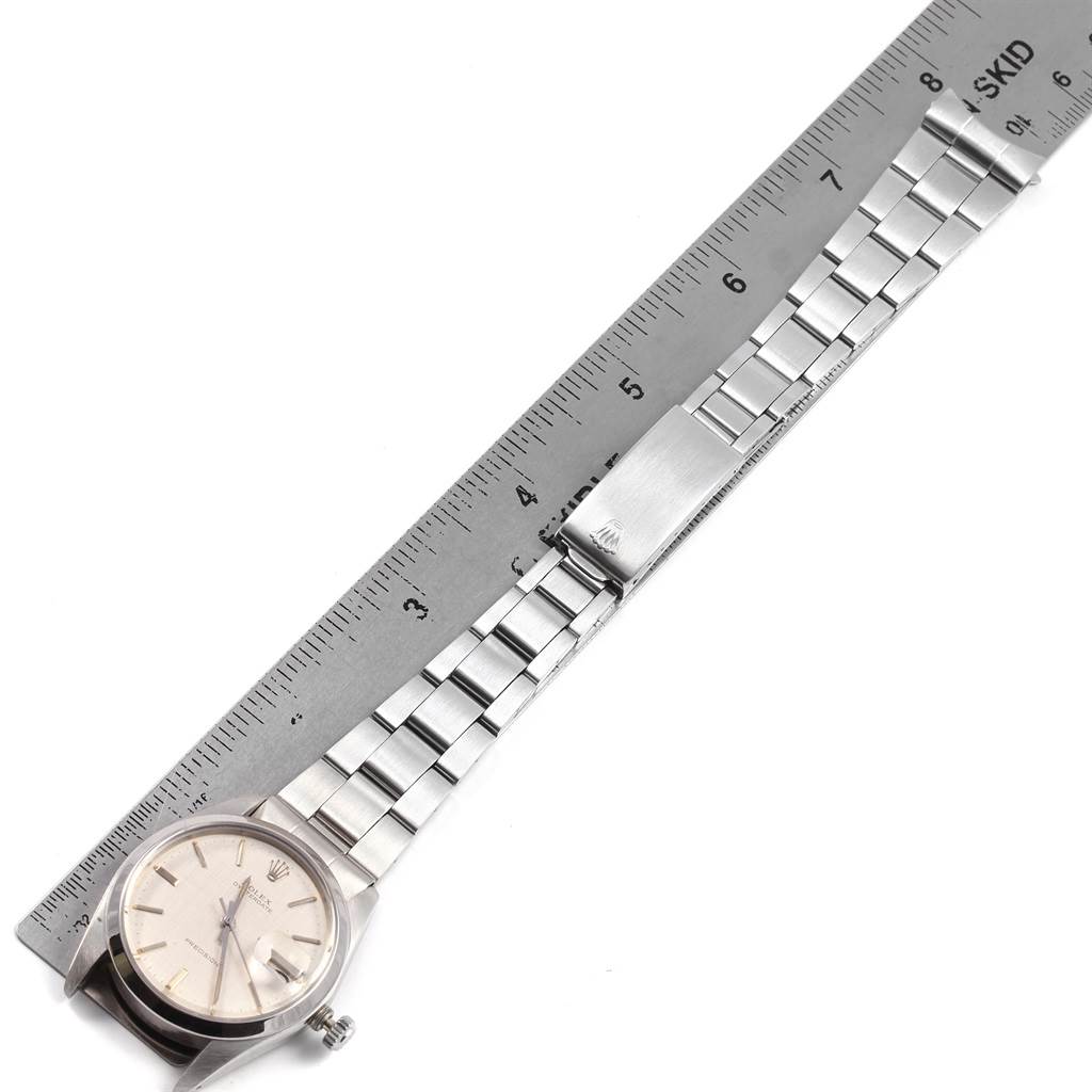 The image shows a Rolex Vintage Collection 6694 Men's Stainless Steel Silver Dial 6694 Men's Stainless Steel Silver Dial watch with a metal bracelet laid flat beside a ruler, displaying the watch face and clasp.