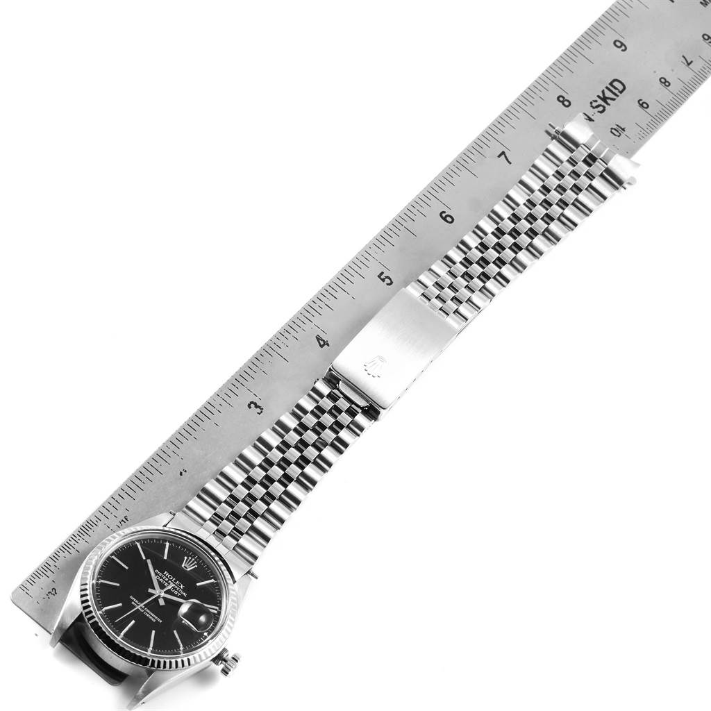 The image shows a top-down view of a Rolex Vintage Collection 16014 Men's Stainless Steel Black Dial 16014 Men's Stainless Steel Black Dial watch, highlighting its face, bracelet, and clasp against a measuring ruler.