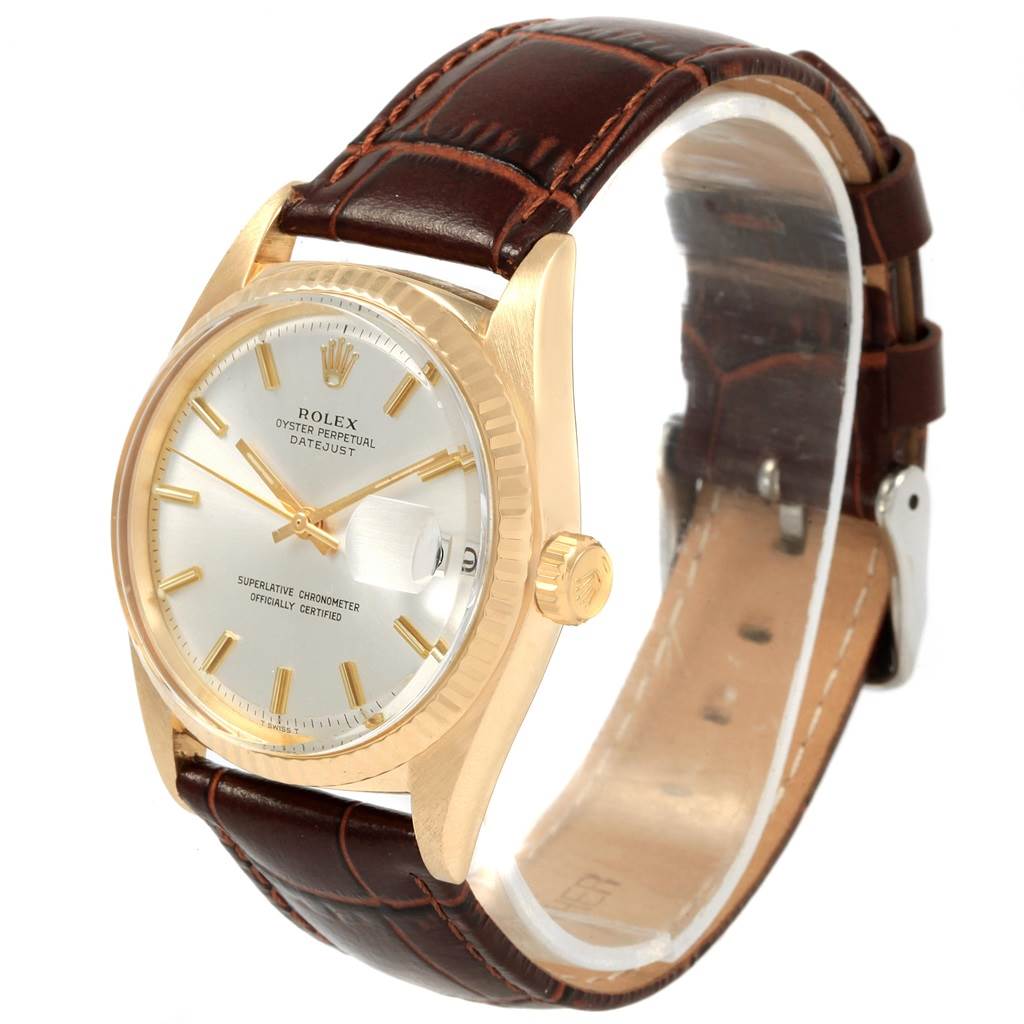 The image shows a vintage Rolex Oyster Perpetual Datejust watch at an angle highlighting its gold case, white dial, and brown leather strap.