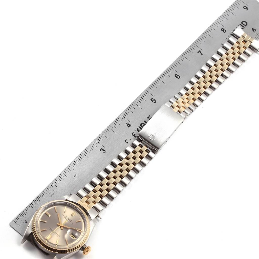 The Rolex Vintage Collection 1601 Men's Steel and Gold (two tone) Grey Dial 1601 Men's Steel and Gold (two tone) Grey Dial watch is shown laid flat next to a ruler, showcasing its face, band, and clasp.