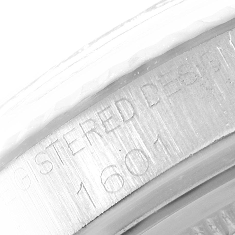 The image shows a close-up of the side of a Rolex Vintage Collection 1601 Men's Stainless Steel Silver Dial 1601 Men's Stainless Steel Silver Dial watch, highlighting its "REGISTERED DESIGN" engraving and model number.