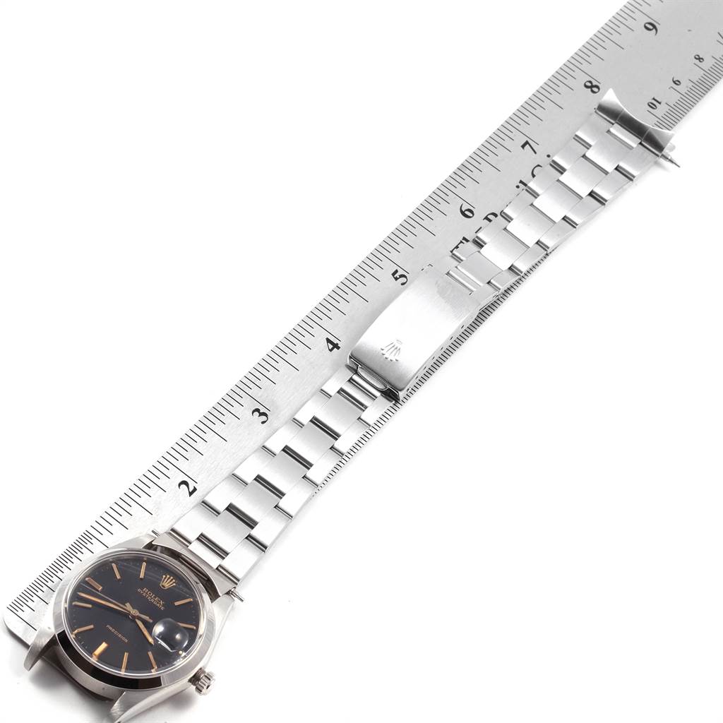 The image shows a top-down view of the Rolex Vintage Collection 6694 Men's Stainless Steel Black Dial 6694 Men's Stainless Steel Black Dial watch, focusing on its face, bracelet, and clasp, alongside a ruler.