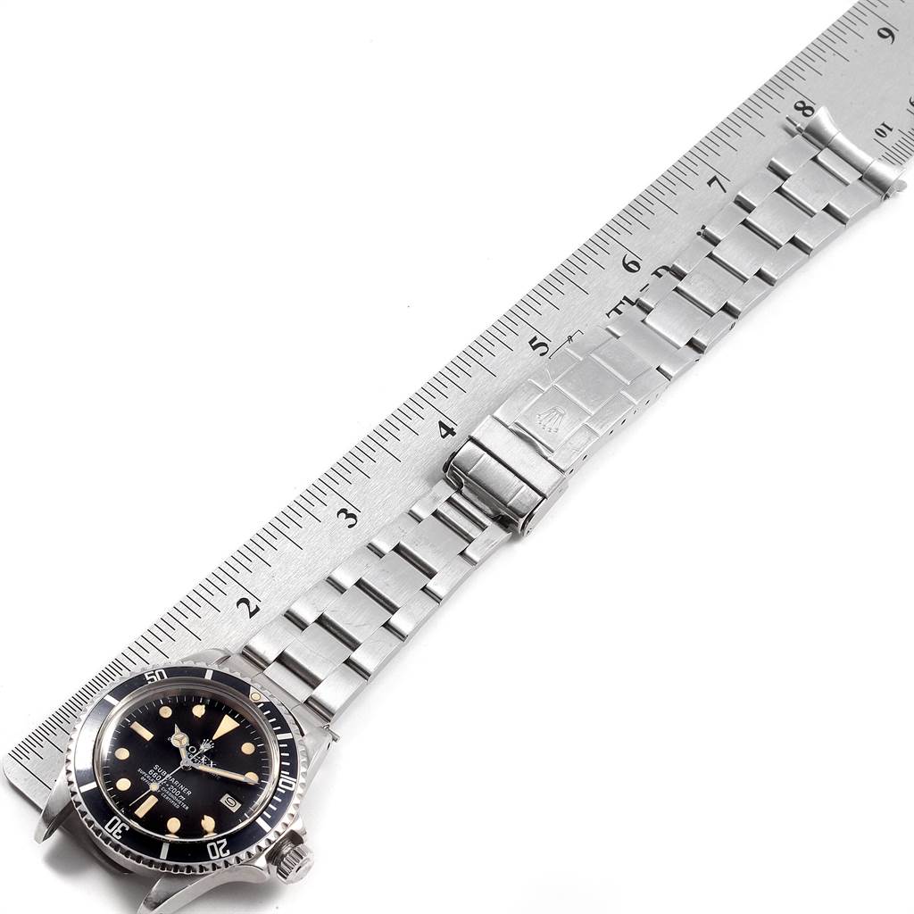 The image shows a top view of the Rolex Vintage Collection 1680 Men's Stainless Steel Black Dial 1680 Men's Stainless Steel Black Dial watch, including the dial, bezel, and metal bracelet laid against a ruler.