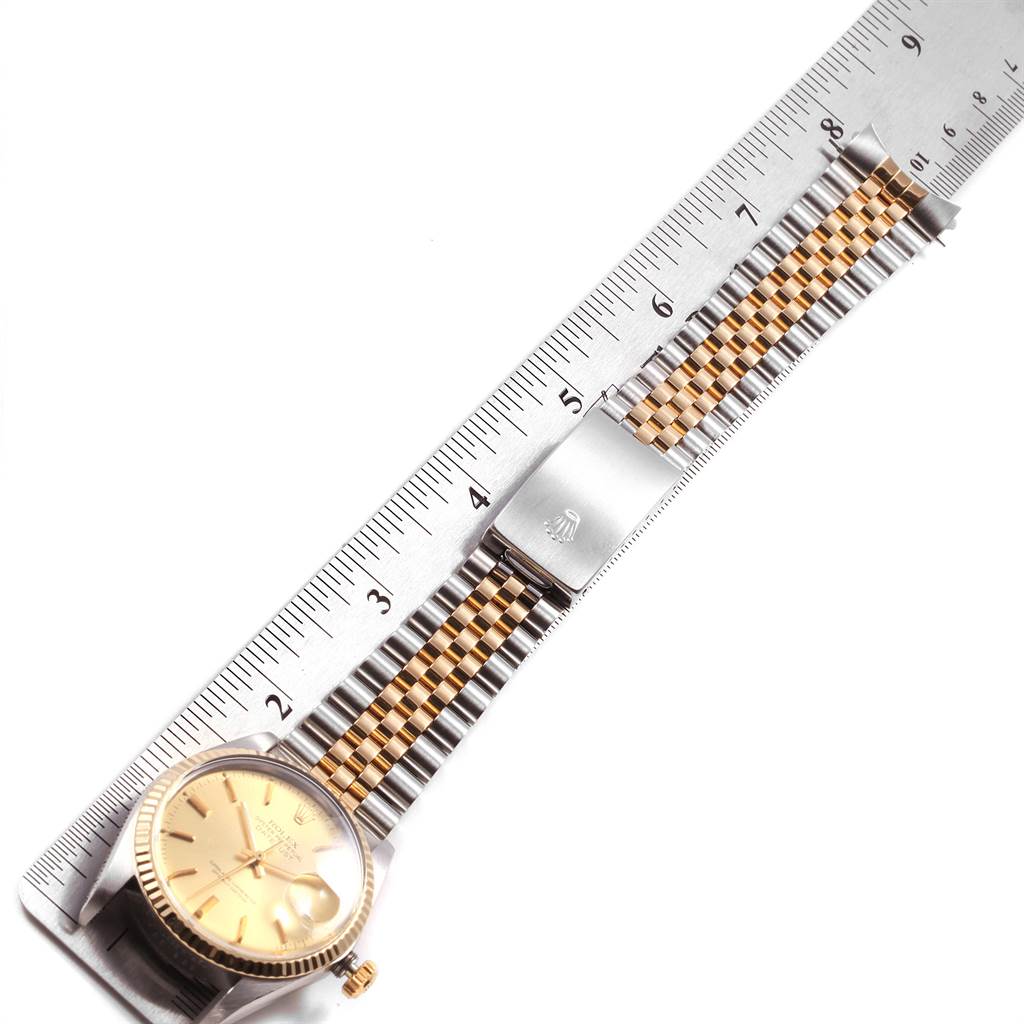 The image shows a Rolex Vintage Collection 16013 Men
s Stainless Steel Champagne Dial 16013 Men
s Stainless Steel Champagne Dial watch measuring its gold and silver bracelet using a ruler, viewed from a top angle.