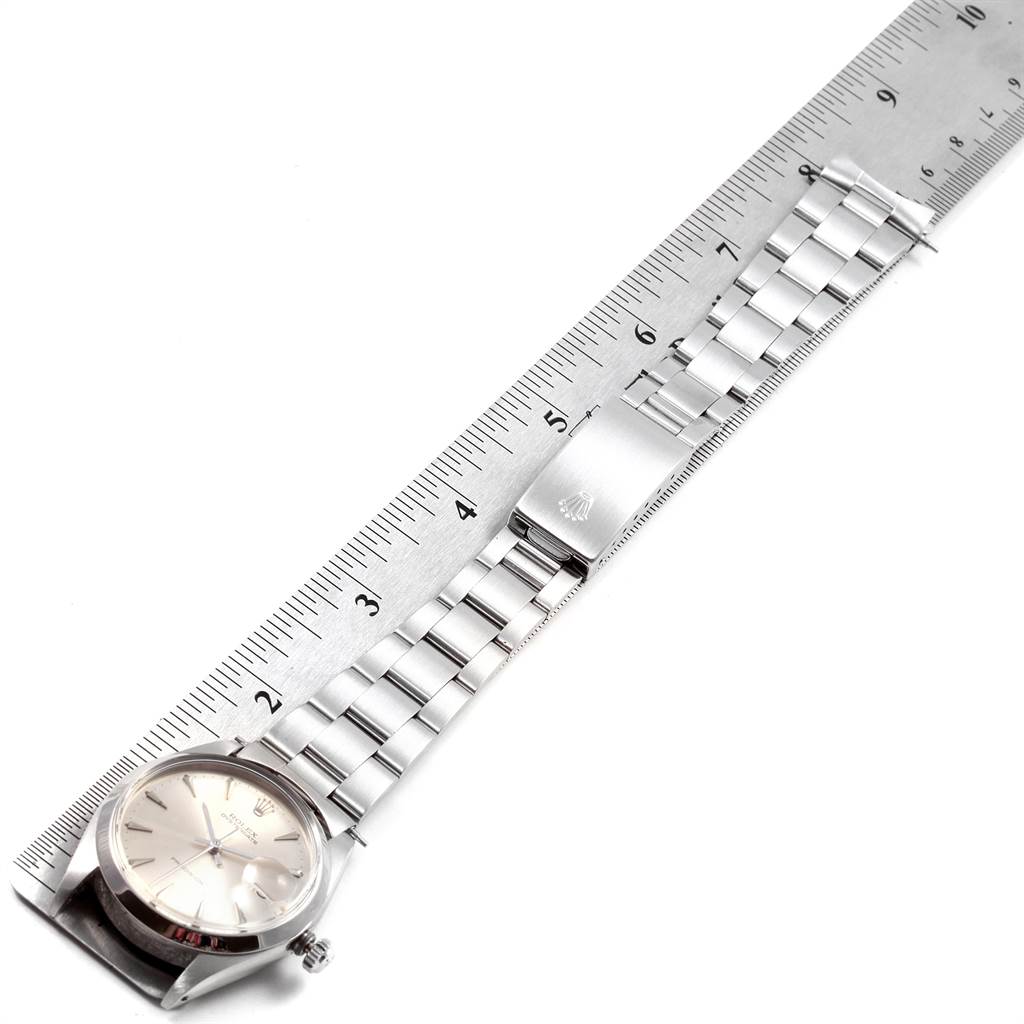 The image shows a Rolex Vintage Collection 6694 Men
s Stainless Steel Silver Dial 6694 Men
s Stainless Steel Silver Dial watch laid flat on a measuring ruler, displaying its face and entire bracelet.