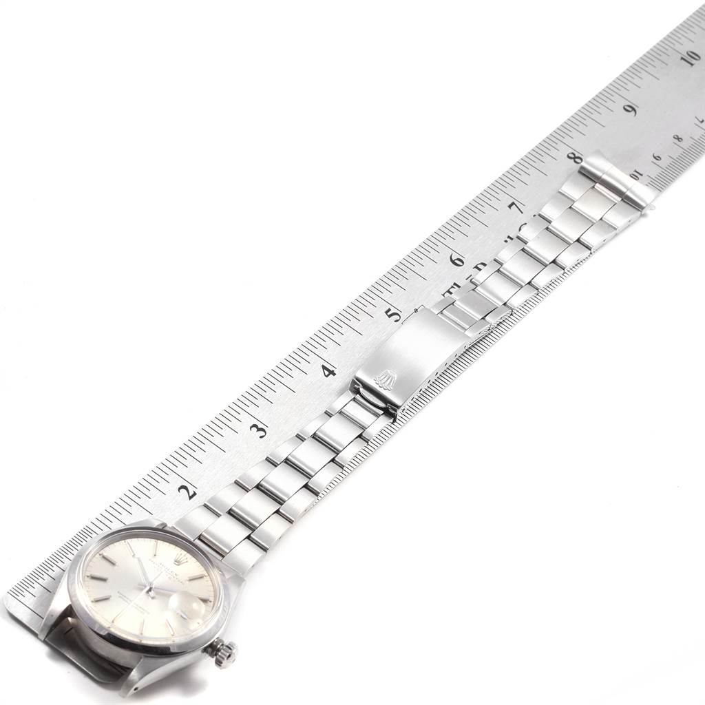 The image shows the Rolex Vintage Collection 1500 Men
s Stainless Steel Silver Dial 1500 Men
s Stainless Steel Silver Dial watch from an overhead angle, highlighting its face, bracelet, and clasp alongside a ruler.