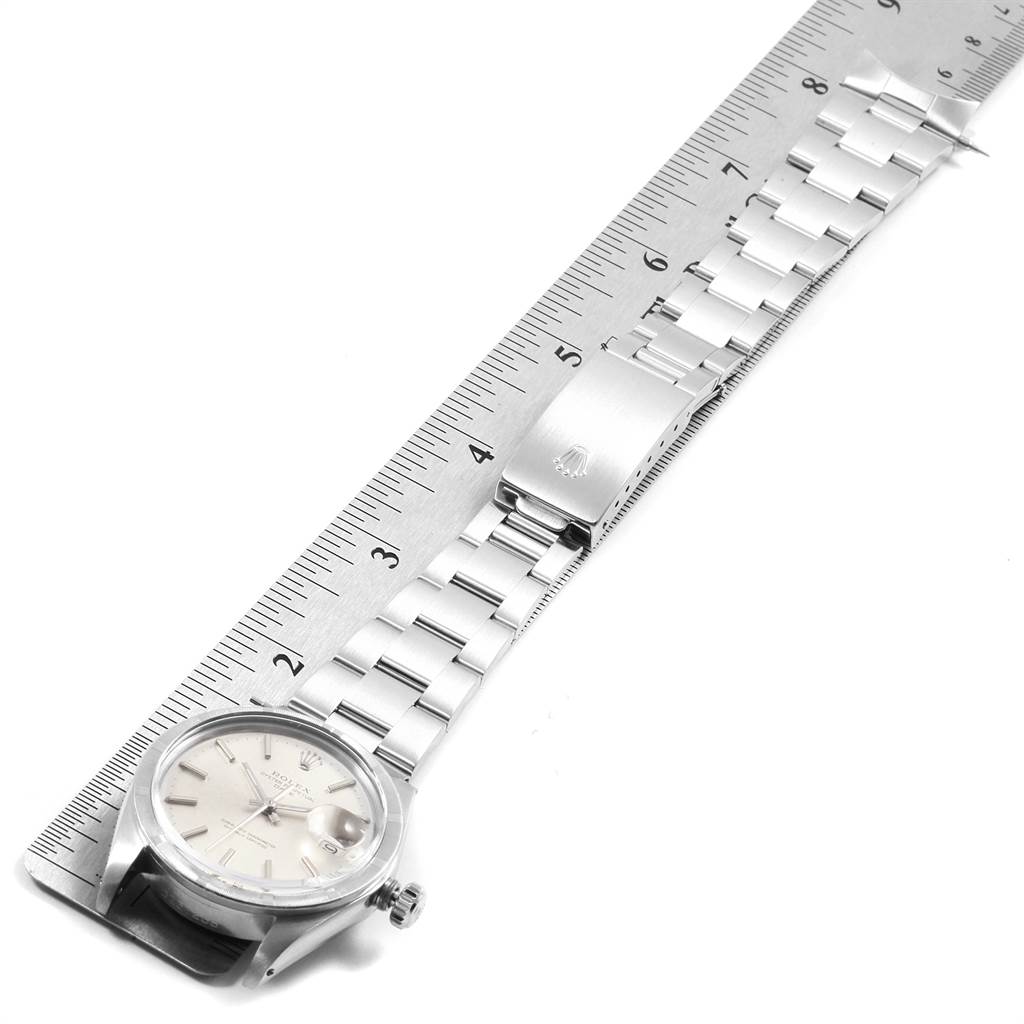 The image shows the side view of a Rolex Vintage Collection 1501 Men
s Stainless Steel Silver Dial 1501 Men
s Stainless Steel Silver Dial watch with its bracelet laid flat against a ruler.
