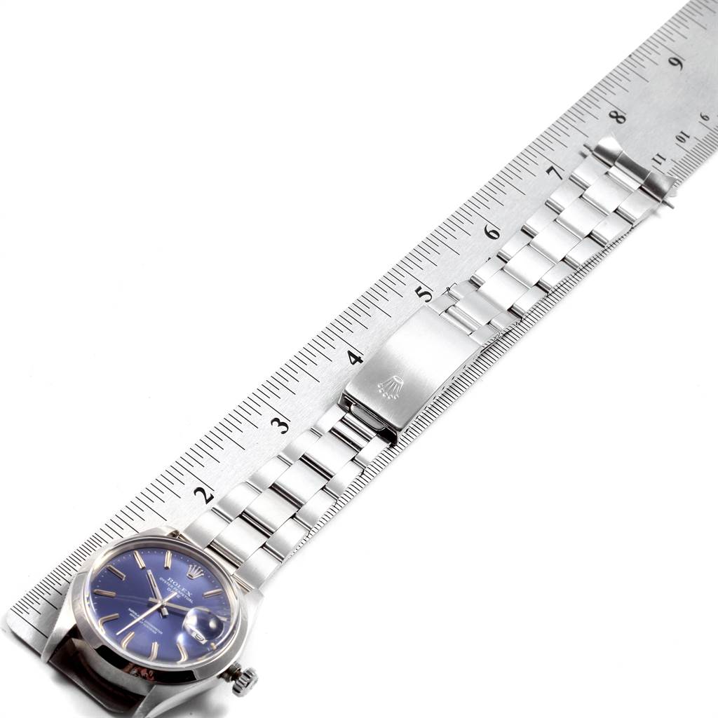 The image shows a side angle of a Rolex Vintage Collection 1500 Men's Stainless Steel Blue Dial 1500 Men's Stainless Steel Blue Dial watch, highlighting the clasp, bracelet, and the face alongside a ruler for scale.