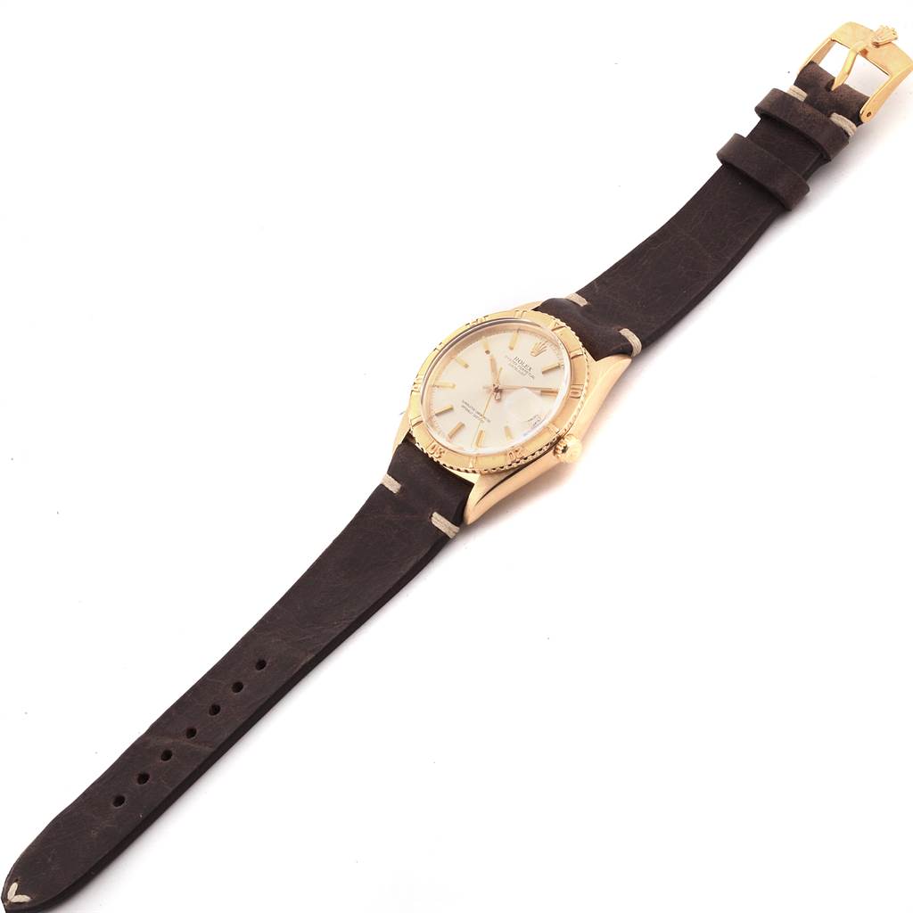 The Rolex Vintage Collection 1625 Men
s Yellow Gold Silver Dial 1625 Men
s Yellow Gold Silver Dial watch is displayed from a top-down angle, showing its face, bezel, crown, and leather strap.