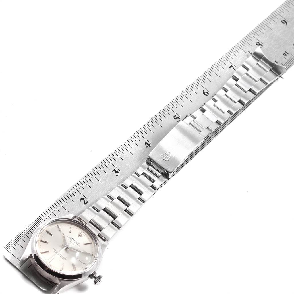This image shows the Rolex Vintage Collection 15000 Men's Stainless Steel Silver Dial 15000 Men's Stainless Steel Silver Dial watch laid flat beside a ruler, showcasing its face, bracelet, and clasp.