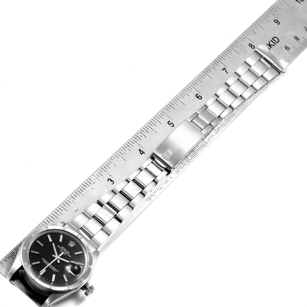 The image shows a top-down angle of a Rolex Vintage Collection 1501 Men's Stainless Steel Black Dial 1501 Men's Stainless Steel Black Dial watch with its bracelet aligned along a metal ruler.