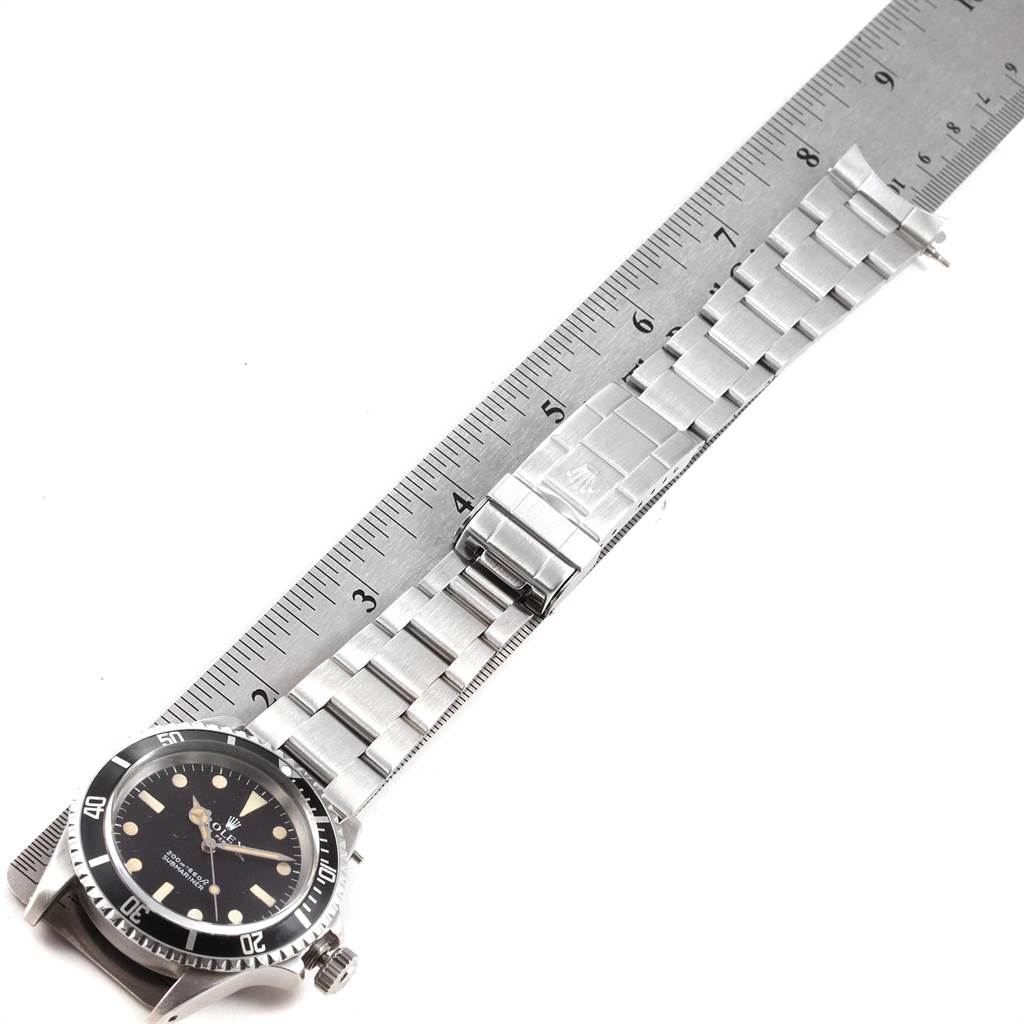 The image shows a side angle of a Rolex Vintage Collection 5513 Men's Stainless Steel Black Dial 5513 Men's Stainless Steel Black Dial watch, highlighting its face, bezel, bracelet, and clasp against a ruler.
