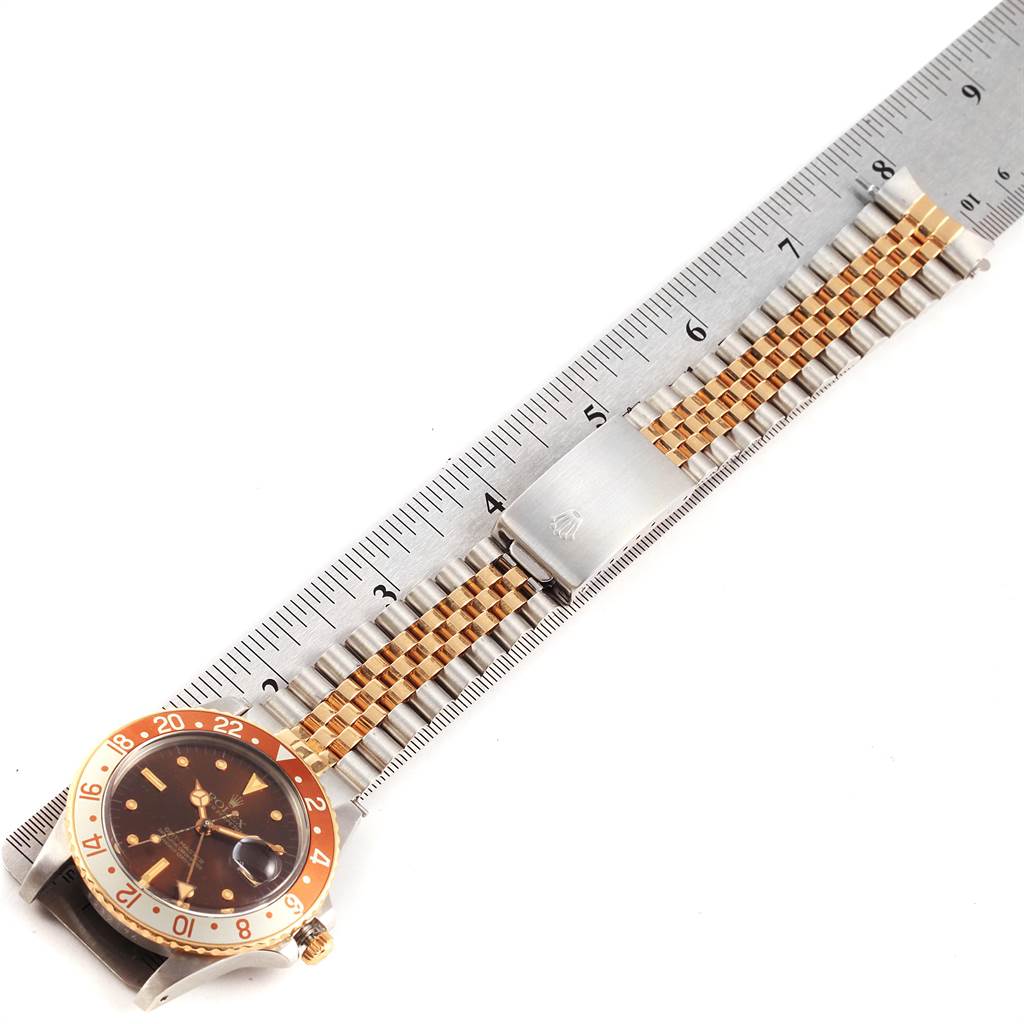 The image shows a side angle of the Rolex Vintage Collection 16753 Men's Stainless Steel Brown Dial 16753 Men's Stainless Steel Brown Dial watch, displaying the face and the metal strap alongside a ruler.