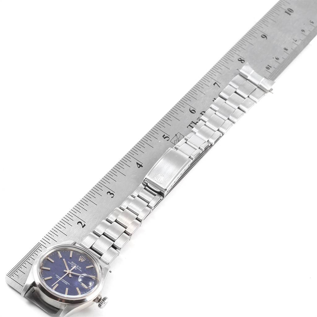 The image shows a Rolex Vintage Collection 1500 Men's Stainless Steel Blue Dial 1500 Men's Stainless Steel Blue Dial watch laid flat next to a ruler, highlighting its face, strap, and clasp.