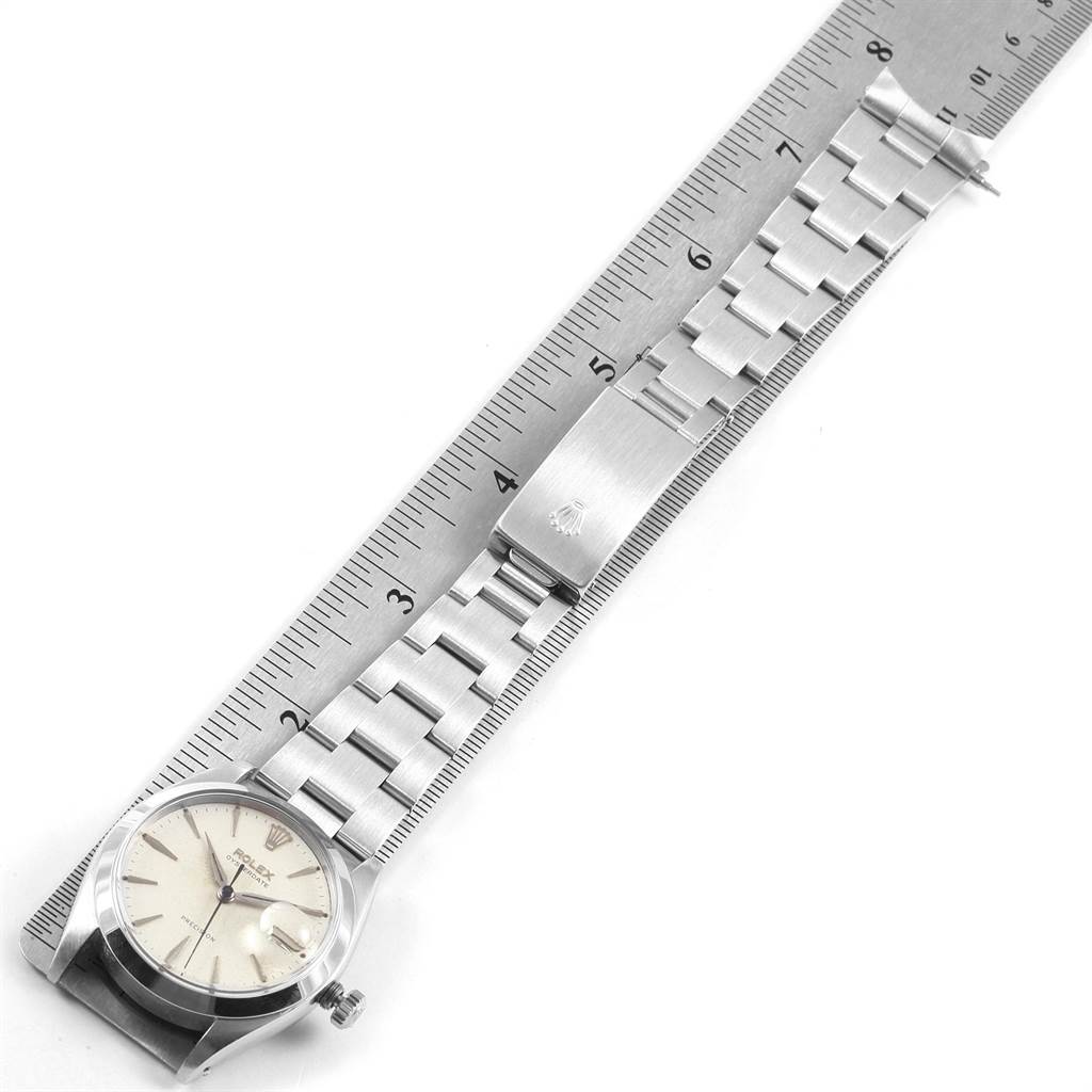 The Rolex Vintage Collection 6694 Men's Stainless Steel Silver Dial 6694 Men's Stainless Steel Silver Dial watch is shown from a top-down angle, with its band aligned alongside a ruler.