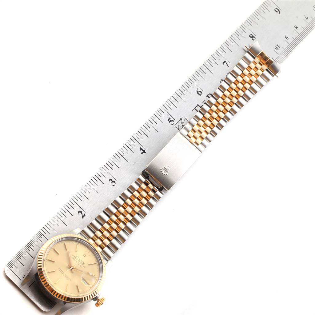 The Rolex Vintage Collection 16013 Men's Stainless Steel Champagne Dial 16013 Men's Stainless Steel Champagne Dial watch is shown from a top-down angle, featuring its face and two-tone metal bracelet alongside a ruler.