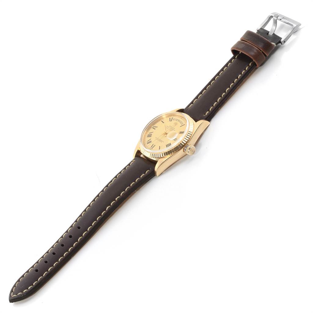 The image shows a side angle view of a Vintage Collection Rolex watch with a brown leather strap and a polished gold case.