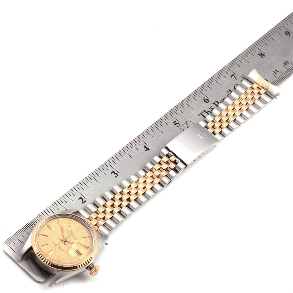 The image shows a top view of a Rolex Vintage Collection 16013 Men's Stainless Steel Champagne Dial 16013 Men's Stainless Steel Champagne Dial watch with its face, bezel, and bracelet next to a ruler for scale.