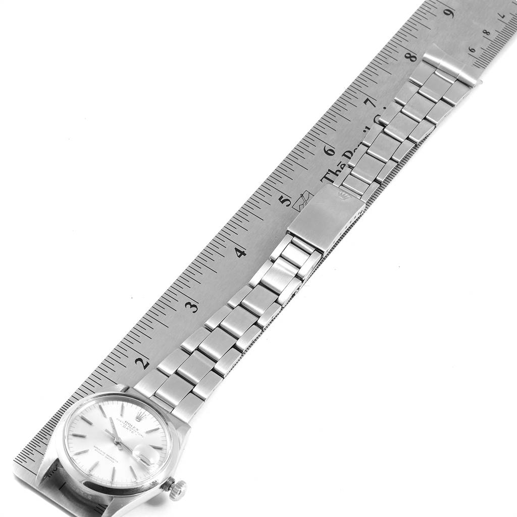The image shows a Rolex Vintage Collection 1500 Men's Stainless Steel Silver Dial 1500 Men's Stainless Steel Silver Dial model watch lying flat with its face, strap, and clasp visible, alongside a ruler.