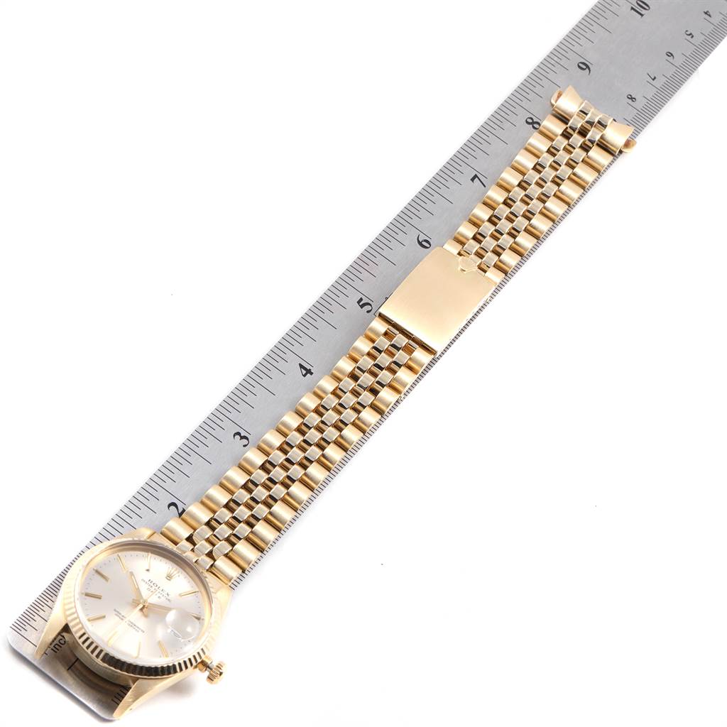 The Vintage Collection Rolex watch is shown flat with its gold band extended adjacent to a ruler.