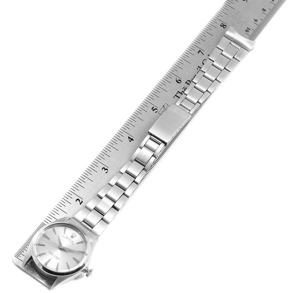 The image shows a Rolex Vintage Collection 1002 Men's Stainless Steel Silver Dial 1002 Men's Stainless Steel Silver Dial watch laid flat on a ruler, displaying the full watch, including the face, bracelet, and clasp.