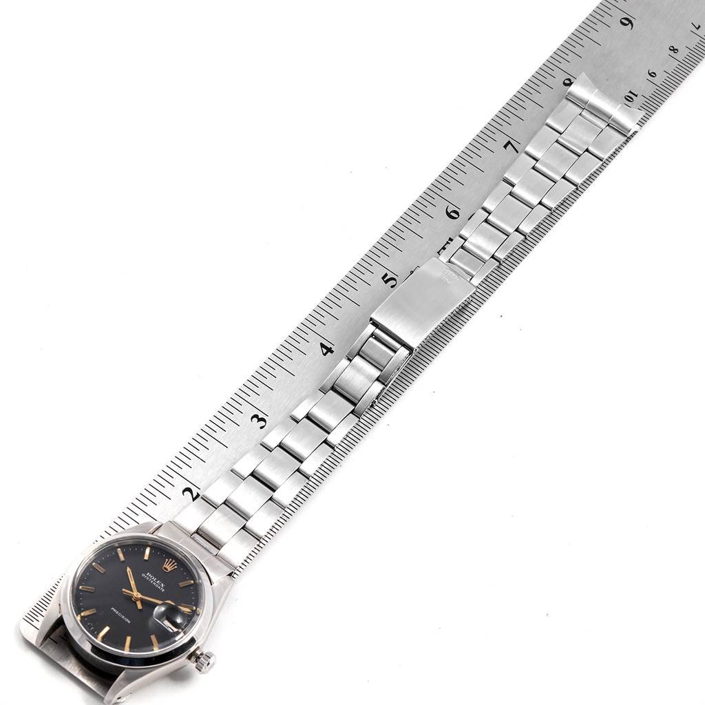 The Rolex Vintage Collection 6694 Men's Stainless Steel Black Dial 6694 Men's Stainless Steel Black Dial watch is shown lying flat with the watch face, bracelet, and clasp visible, alongside a measuring ruler.