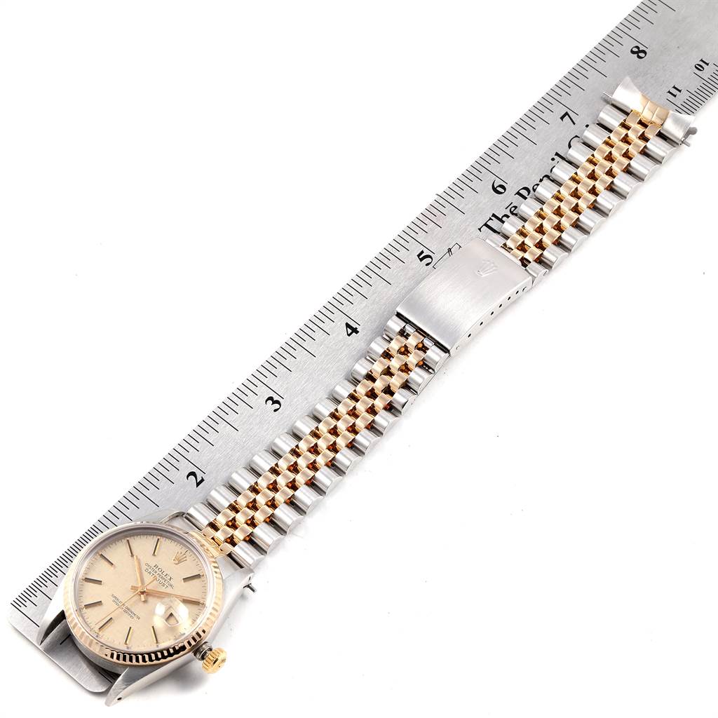 The image shows a side view of a Rolex Vintage Collection 16013 Men's Stainless Steel Champagne Dial 16013 Men's Stainless Steel Champagne Dial watch, featuring its band and dial, placed next to a ruler.
