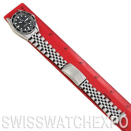 The image shows a top-down view of a Tudor Submariner 90910 Men's Stainless Steel Black Dial 90910 Men's Stainless Steel Black Dial watch, alongside a ruler which measures the length of the watch and its metal bracelet.