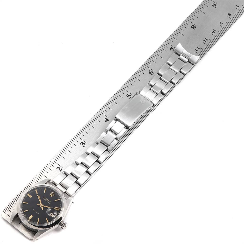 The image shows a top-down view of a Rolex Vintage Collection 6694 Men's Stainless Steel Black Dial 6694 Men's Stainless Steel Black Dial watch alongside a ruler, highlighting the face and the metal bracelet.