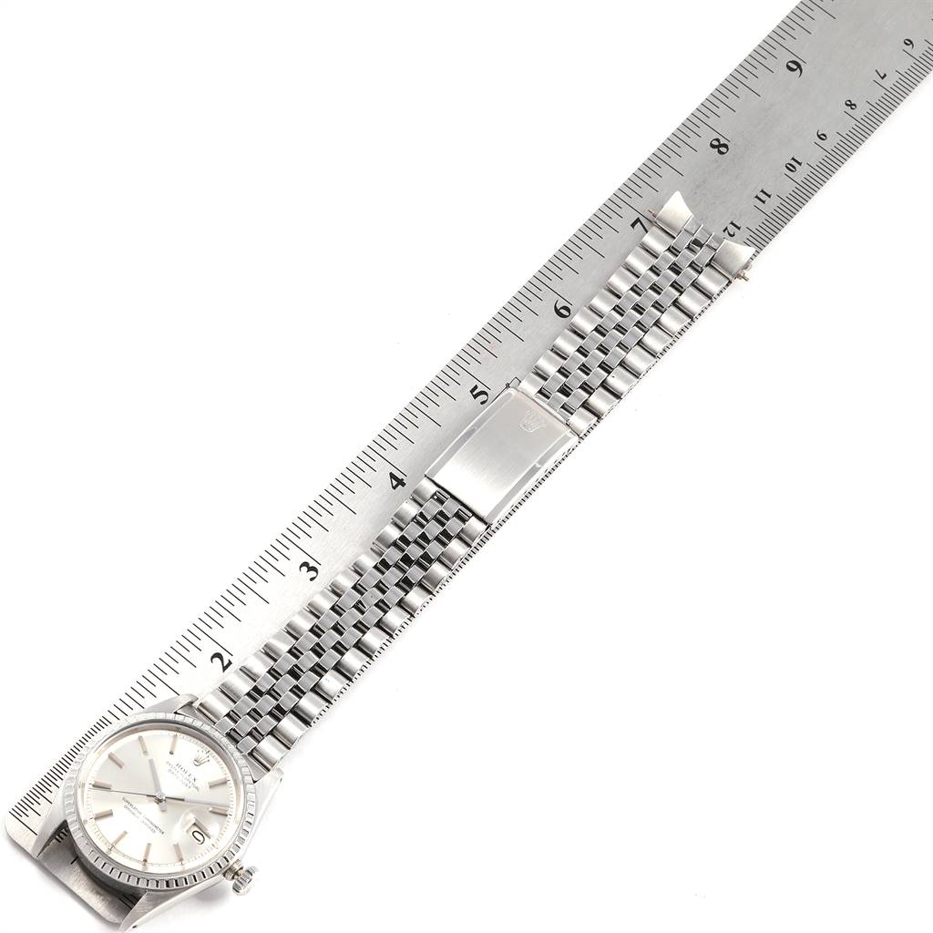 The image shows a Rolex Vintage Collection 1603 Men's Stainless Steel Silver Dial 1603 Men's Stainless Steel Silver Dial watch laid flat next to a ruler, displaying its face and metal strap.