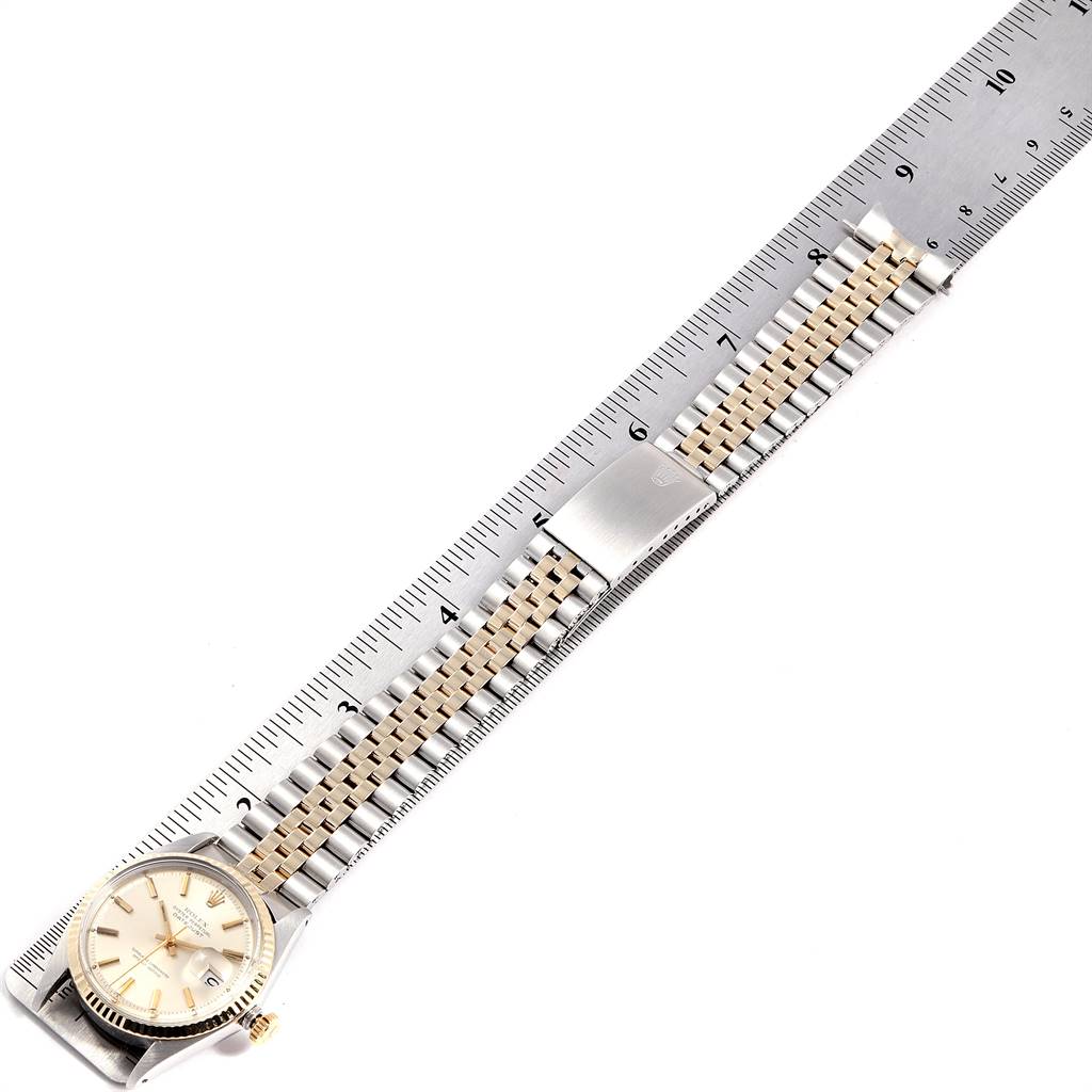 The image shows a Rolex Vintage Collection 1601 Men
s Steel and Gold (two tone) Silver Dial 1601 Men
s Steel and Gold (two tone) Silver Dial watch laid flat with its dial and bracelet in full view alongside a ruler for scale.