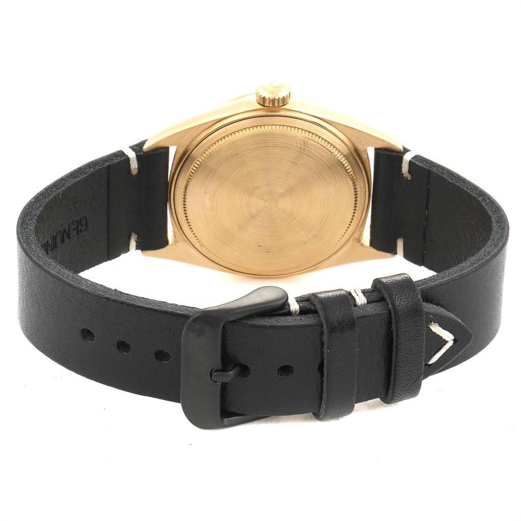 The image shows the back of a Rolex Vintage Collection 1803 Men's Yellow Gold Black Dial 1803 Men's Yellow Gold Black Dial watch featuring a black leather strap and a gold case.