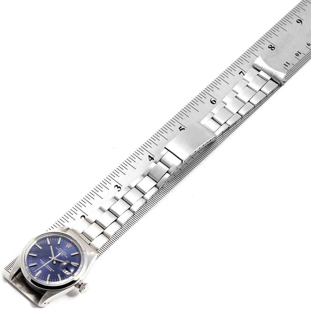 This image shows a Rolex Vintage Collection 1500 Men's Stainless Steel Blue Dial 1500 Men's Stainless Steel Blue Dial watch with a blue dial and metal band measured against a ruler at an oblique angle.