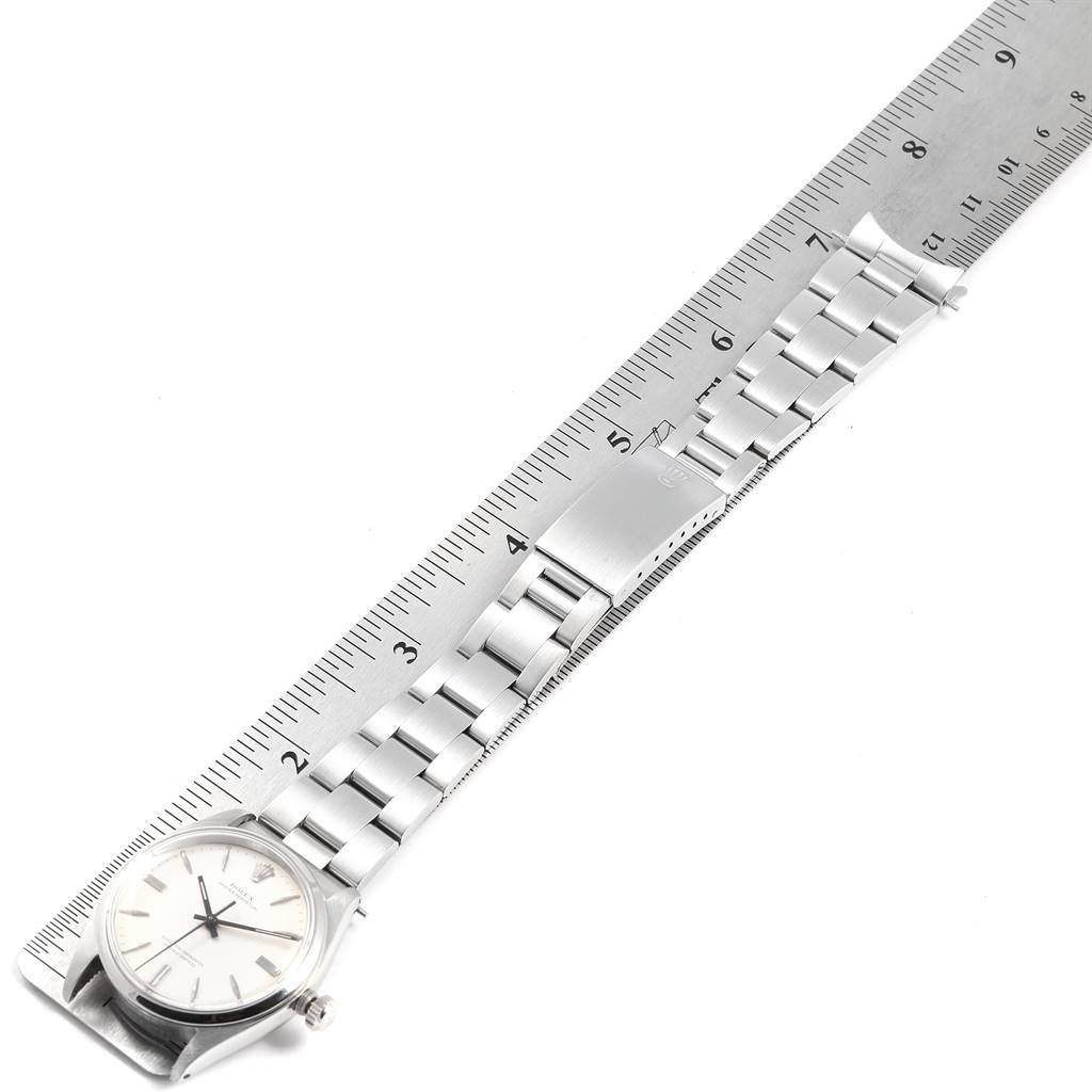 The image shows a top view of a Rolex Vintage Collection 1002 Men
s Stainless Steel Silver Dial 1002 Men
s Stainless Steel Silver Dial watch alongside a metal ruler for scale.