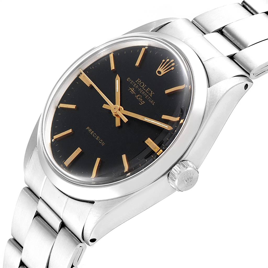 The Vintage Collection Rolex watch is shown at an oblique angle, highlighting the black dial, gold markers, and stainless steel bracelet.