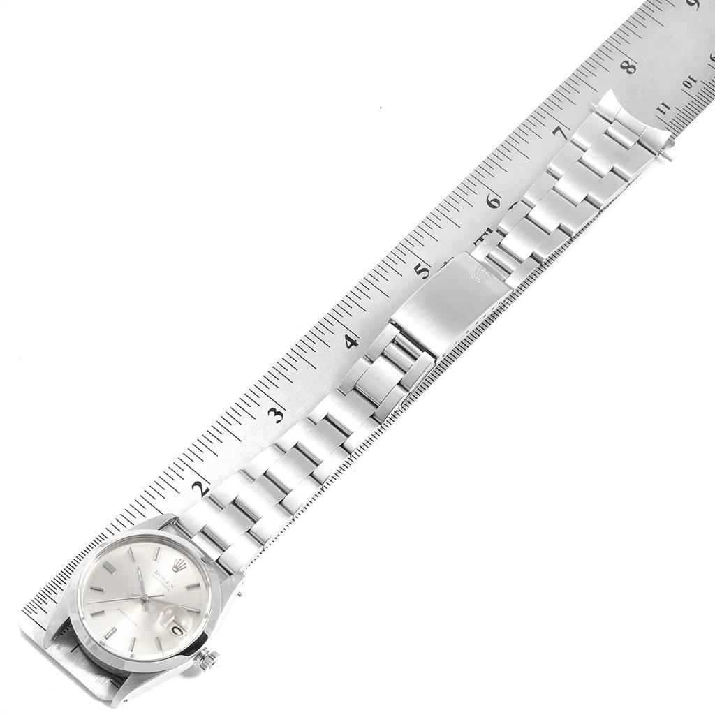 The image shows a Rolex Vintage Collection 6694 Men
s Stainless Steel Silver Dial 6694 Men
s Stainless Steel Silver Dial watch laid flat with a ruler, highlighting the bracelet and clasp.