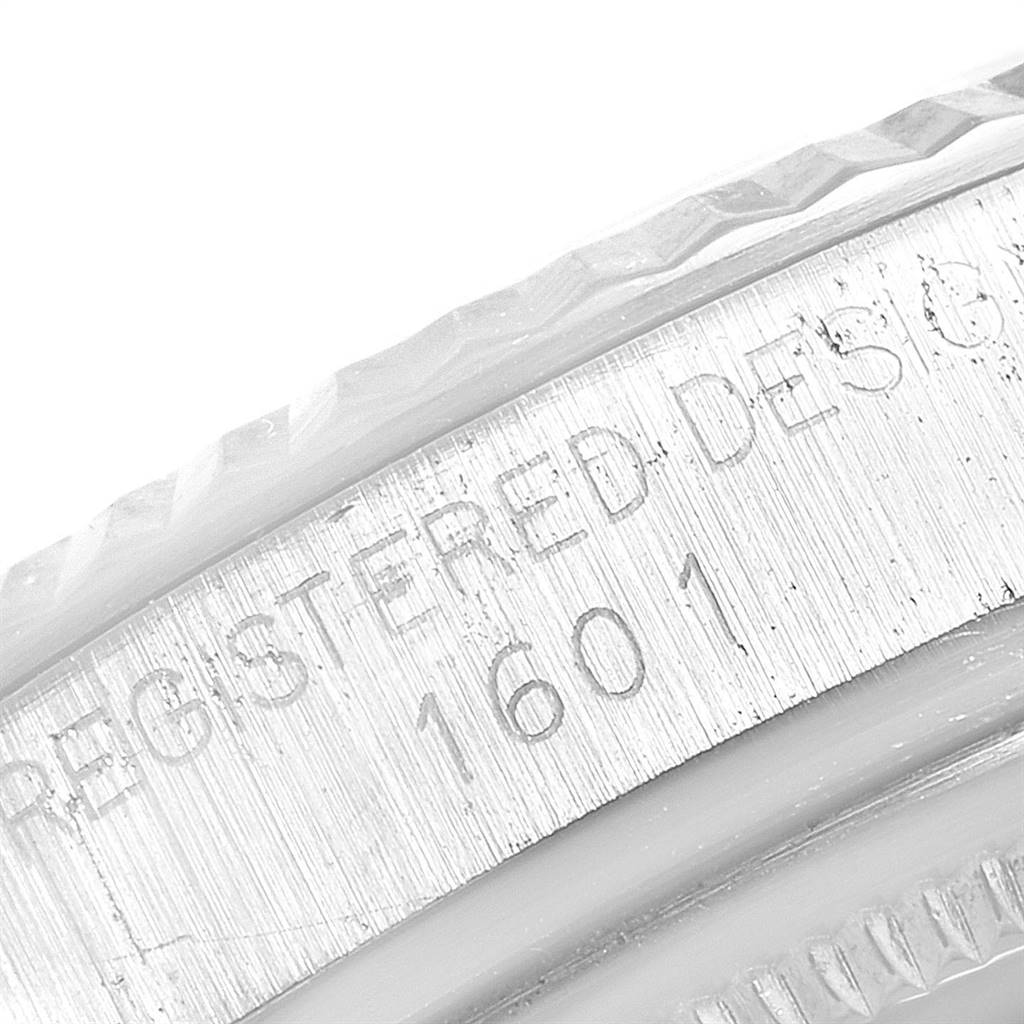 The image shows a close-up of the edge and serial number engraving on the Vintage Collection model 1601 by Rolex.