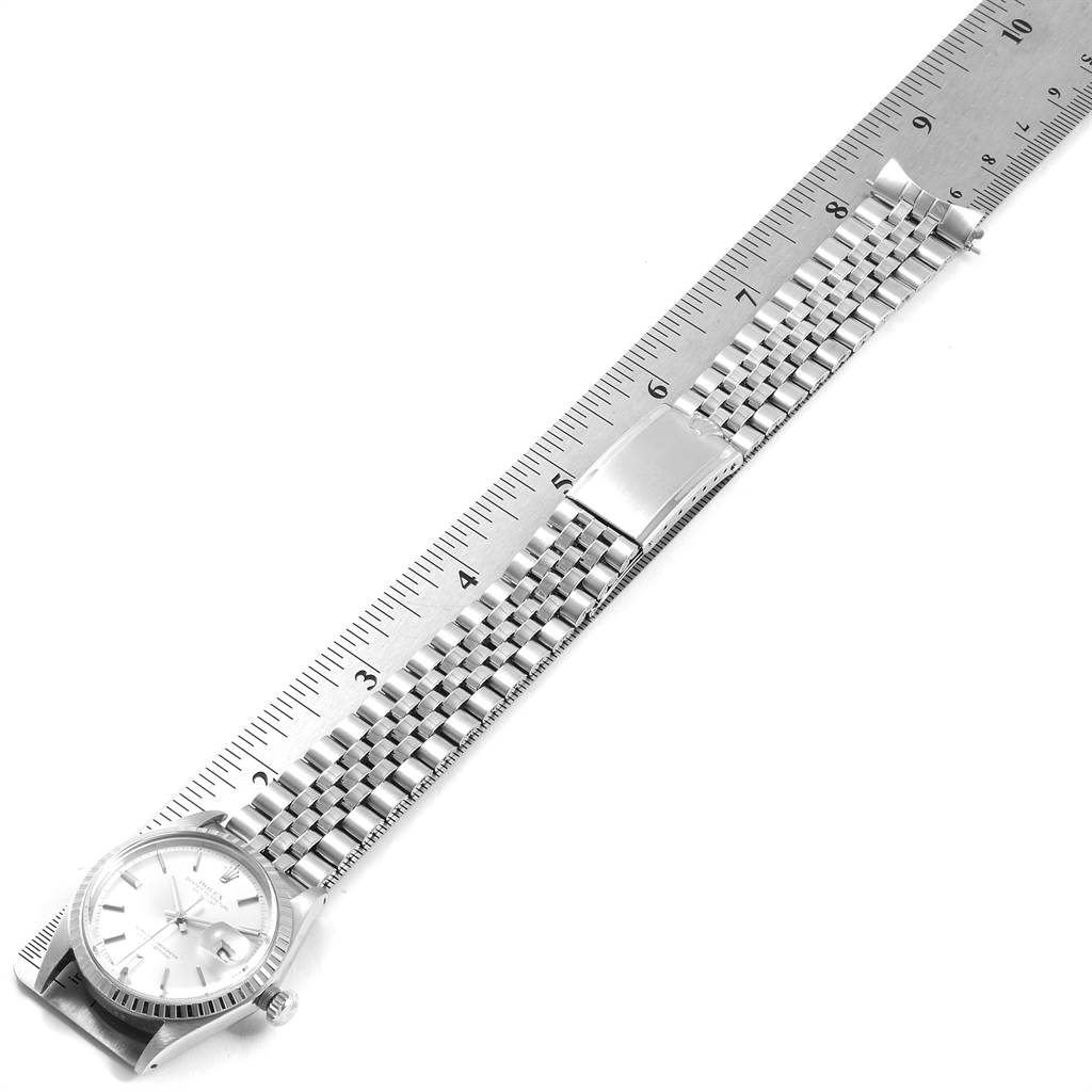 The image shows a horizontal view of a Rolex Vintage Collection 1603 Men
s Stainless Steel Silver Dial 1603 Men
s Stainless Steel Silver Dial watch placed alongside a ruler, focusing on the watch face and bracelet.