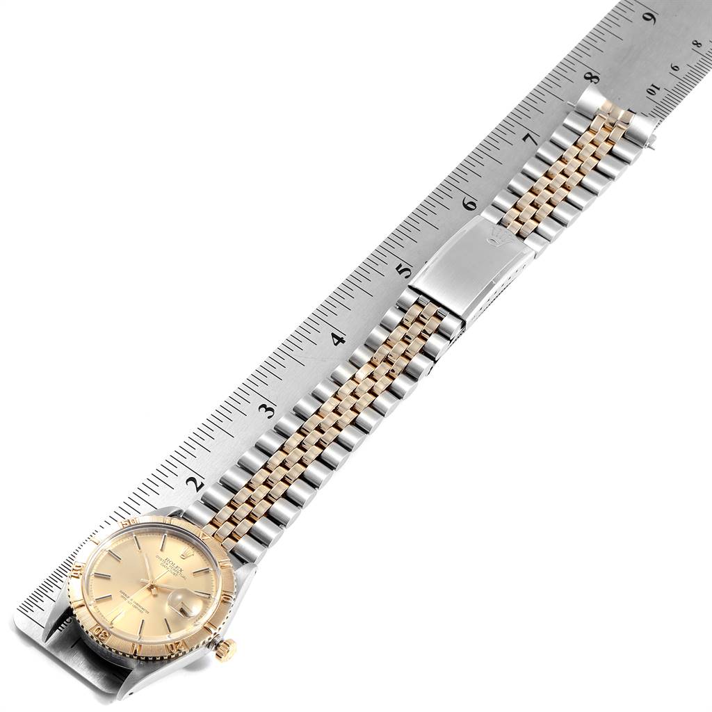 The image shows the front view of a Rolex Vintage Collection 1625 Men
s Steel and Gold (two tone) Champagne Dial 1625 Men
s Steel and Gold (two tone) Champagne Dial watch with its bracelet laid out alongside a ruler.