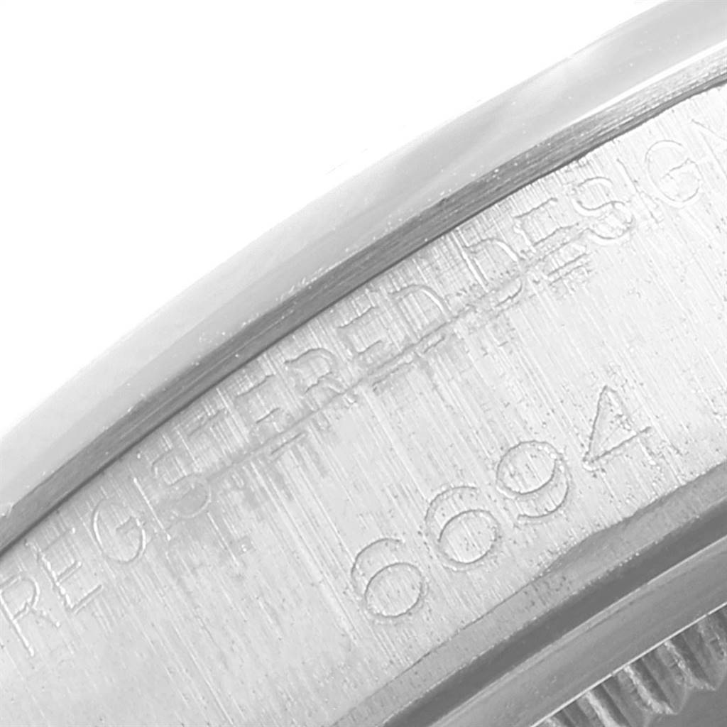 The image shows an extreme close-up of the case side of a Rolex Vintage Collection 6694 Men's Stainless Steel Black Dial 6694 Men's Stainless Steel Black Dial watch, highlighting the engraved model number 6694.