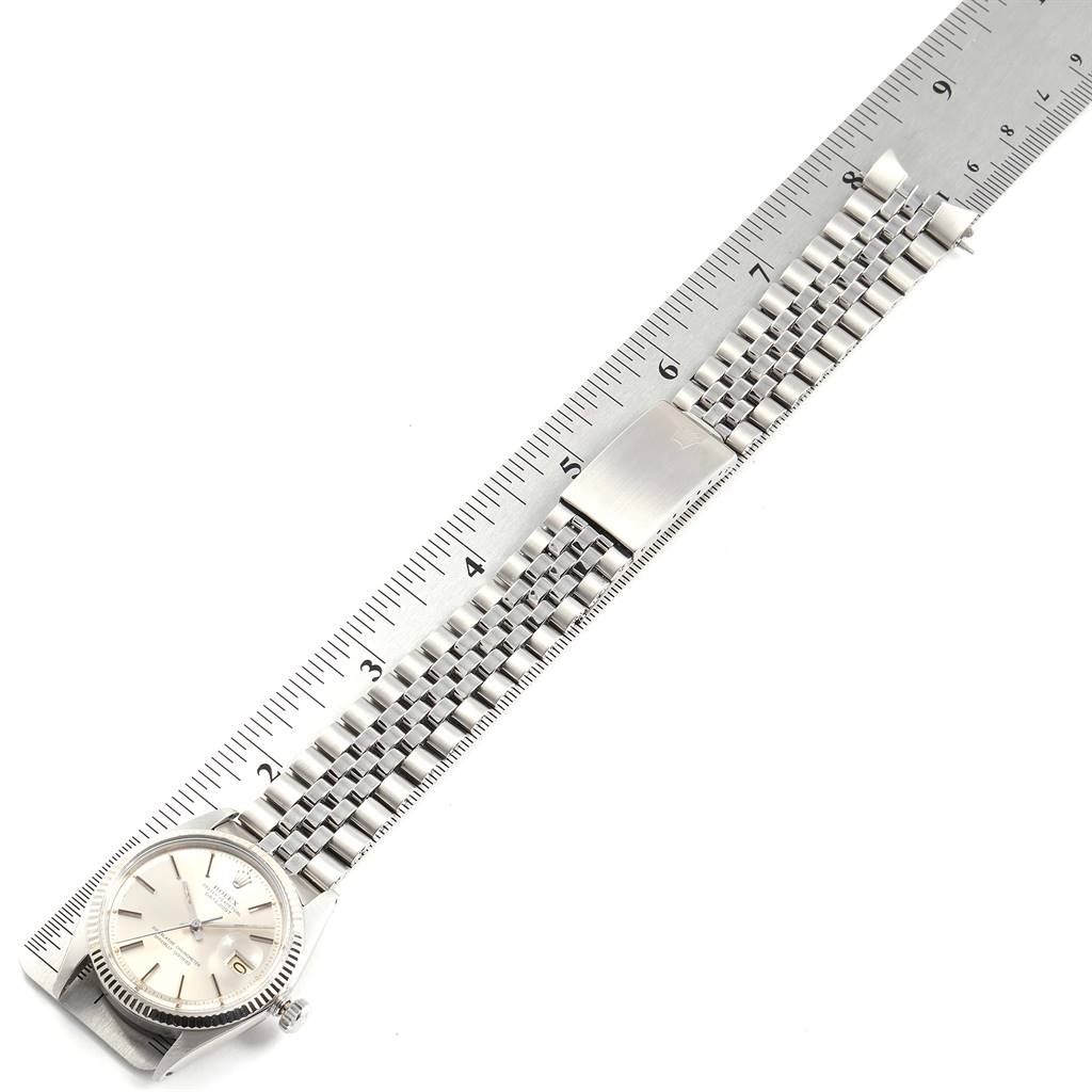 The image shows a side view of a Rolex Vintage Collection 1601 Men
s Stainless Steel Silver Dial 1601 Men
s Stainless Steel Silver Dial model watch, highlighting its bracelet and clasp alongside a ruler.