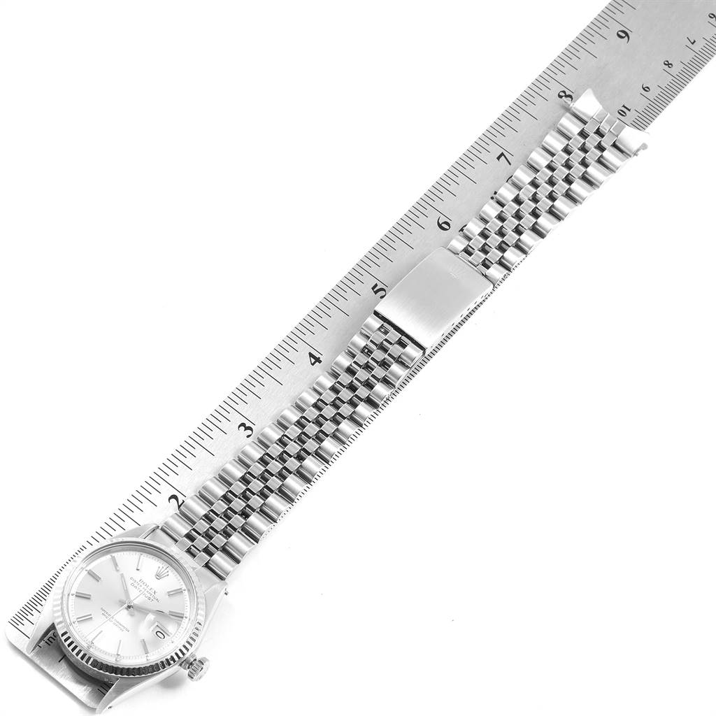 The image shows a Rolex Vintage Collection 1601 Men
s Stainless Steel Silver Dial 1601 Men
s Stainless Steel Silver Dial watch laid flat with a metal ruler measuring its length.