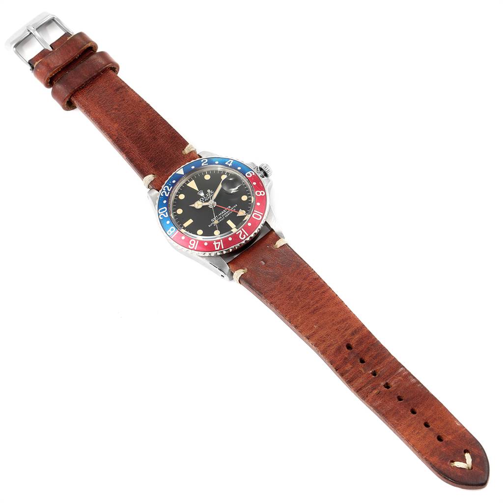 The Vintage Collection Rolex watch is shown at an oblique angle, highlighting its brown leather strap and colorful bezel.