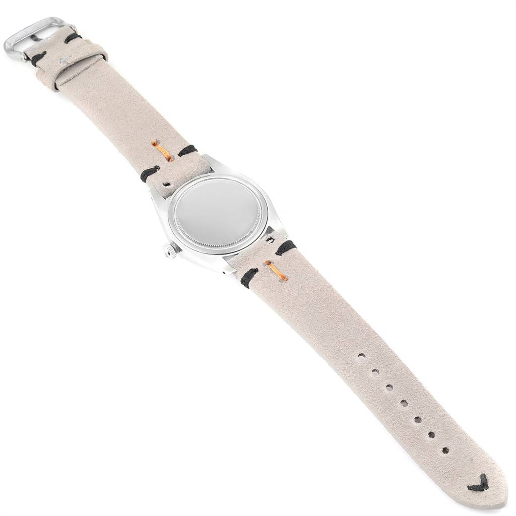 The Vintage Collection Rolex watch is shown from an overhead angle, displaying the face, crown, and suede watch strap.